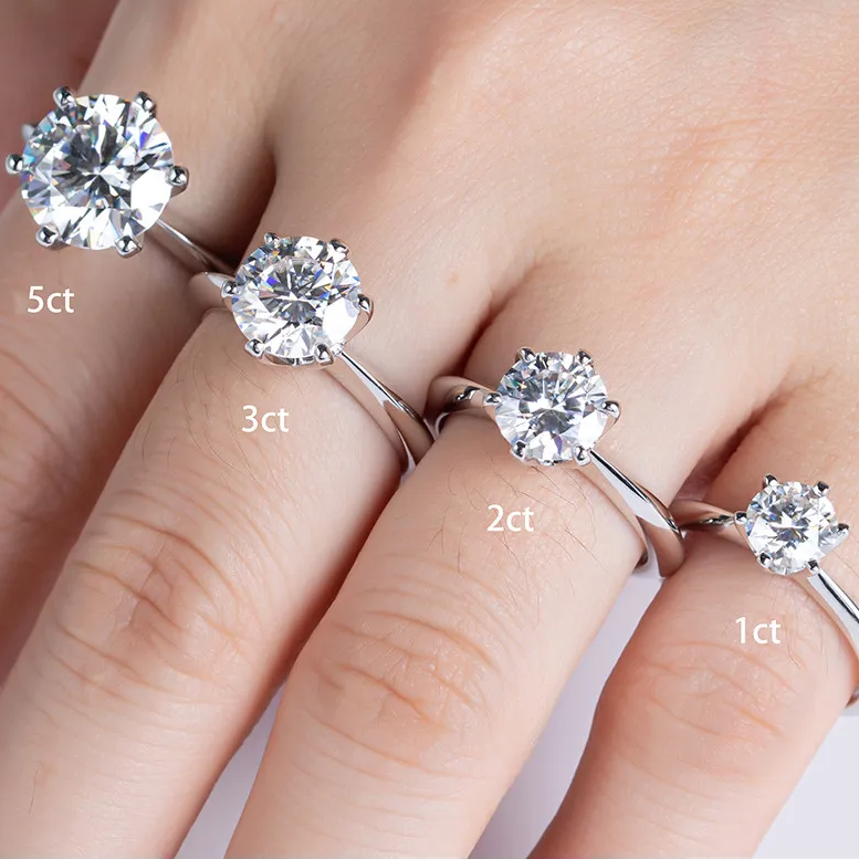 Four diamond rings with varying carat weights on a person's hand.